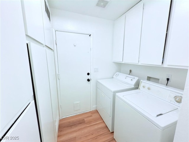 laundry room featuring cabinets, light wood-type flooring, and washing machine and clothes dryer