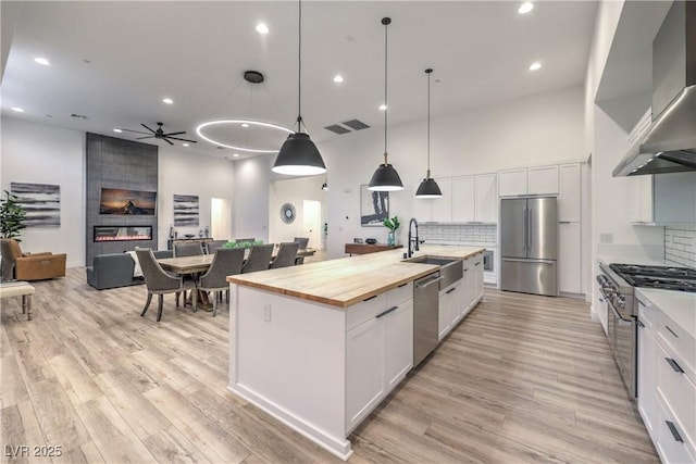 kitchen featuring white cabinetry, pendant lighting, wall chimney exhaust hood, and high quality appliances