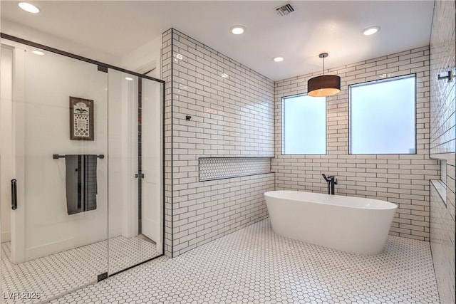 bathroom with tile patterned floors, shower with separate bathtub, and tile walls