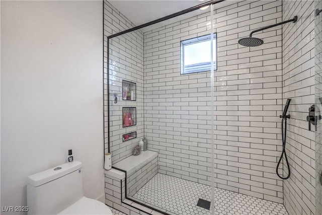 bathroom featuring a shower with door and toilet