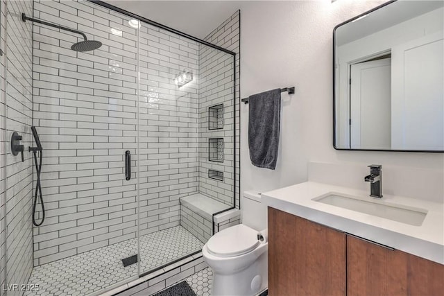 bathroom with a shower with door, vanity, and toilet