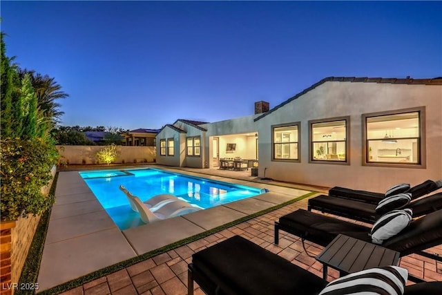 pool at dusk featuring a patio