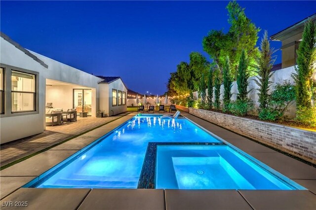 pool at night with an in ground hot tub