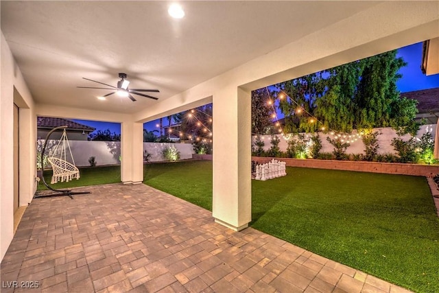 patio at twilight featuring a lawn and ceiling fan