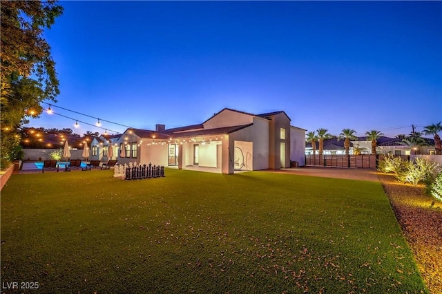 back house at dusk with a lawn