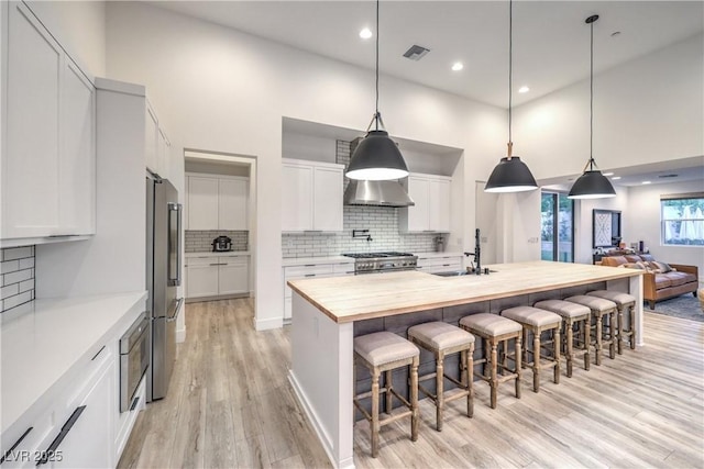 kitchen featuring wooden counters, sink, pendant lighting, and white cabinets