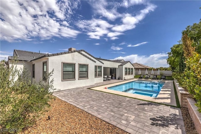 back of property with a swimming pool with hot tub and a patio