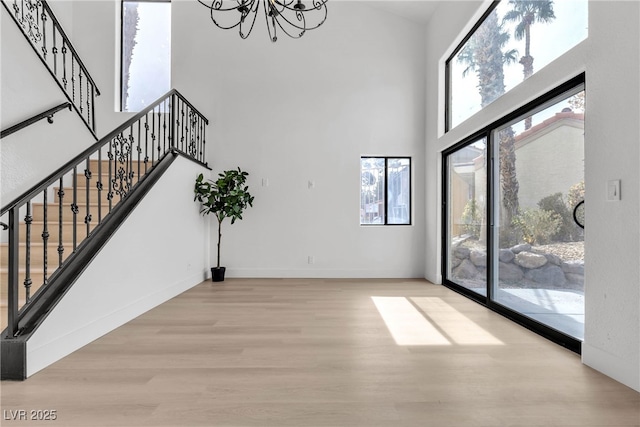 interior space featuring a high ceiling, a notable chandelier, and light hardwood / wood-style flooring