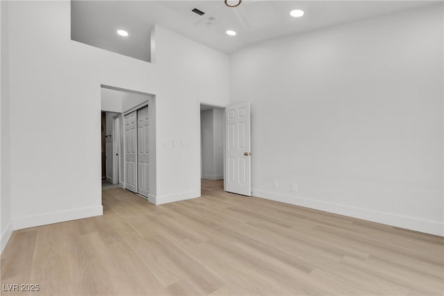 unfurnished bedroom featuring light hardwood / wood-style flooring and a high ceiling