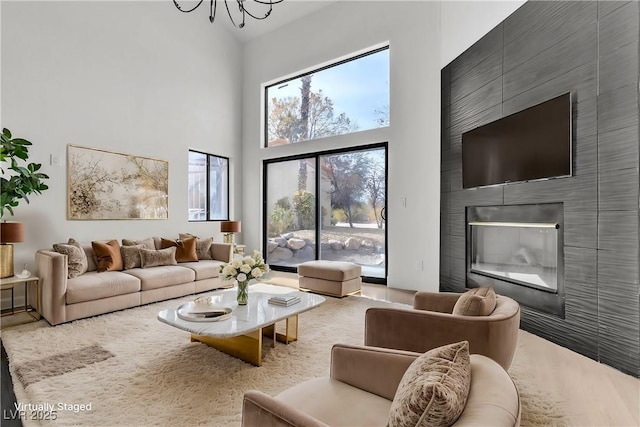 living room featuring a large fireplace, a high ceiling, and an inviting chandelier