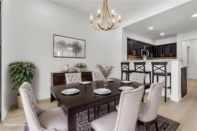 dining area with light wood-type flooring and an inviting chandelier