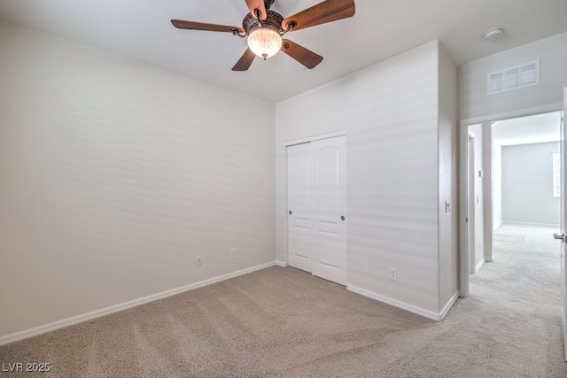 unfurnished bedroom with ceiling fan, light colored carpet, and a closet