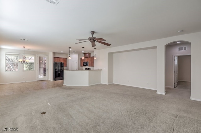 unfurnished living room featuring ceiling fan with notable chandelier and light carpet