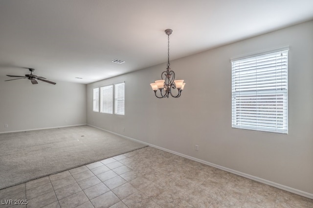 carpeted spare room with ceiling fan with notable chandelier