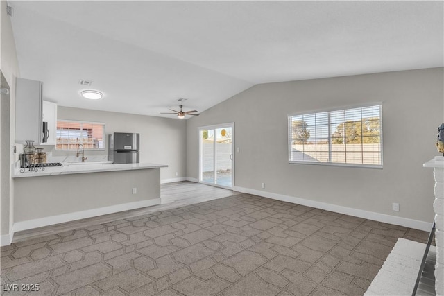 unfurnished living room with plenty of natural light, sink, lofted ceiling, and ceiling fan