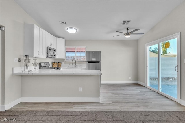 kitchen featuring sink, appliances with stainless steel finishes, light hardwood / wood-style floors, white cabinets, and kitchen peninsula