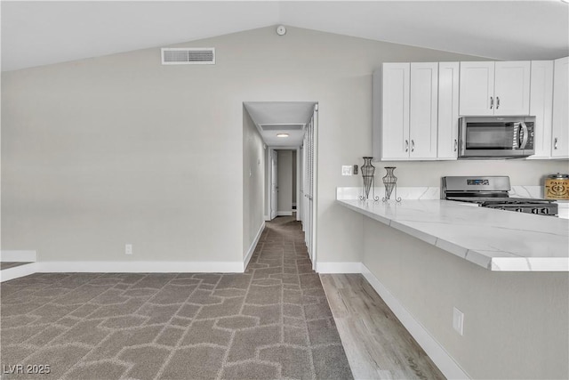 kitchen featuring vaulted ceiling, kitchen peninsula, white cabinets, and appliances with stainless steel finishes