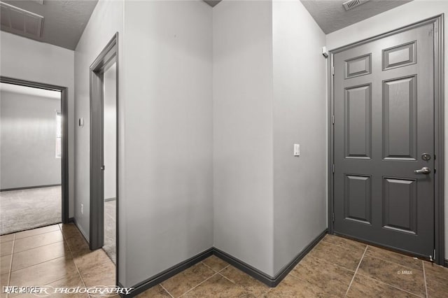 hallway with dark tile patterned floors and a textured ceiling