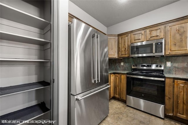 kitchen featuring light tile patterned flooring, appliances with stainless steel finishes, a textured ceiling, and backsplash