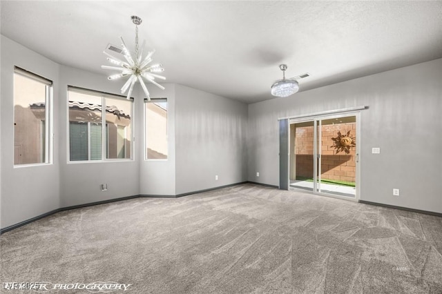 spare room with an inviting chandelier, carpet floors, and a wealth of natural light