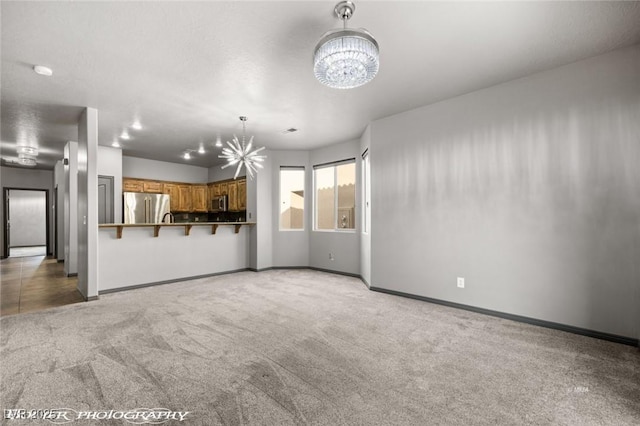 unfurnished living room with carpet flooring and a notable chandelier