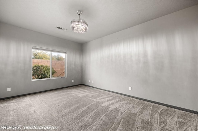 spare room with an inviting chandelier and carpet