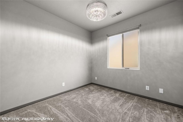 carpeted spare room with a notable chandelier