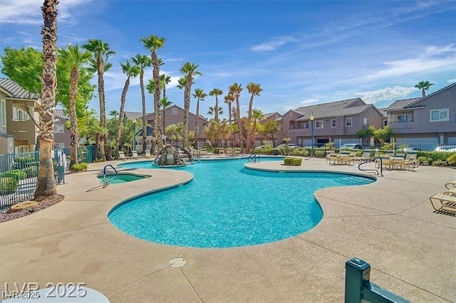 community pool featuring a patio area, fence, and a residential view