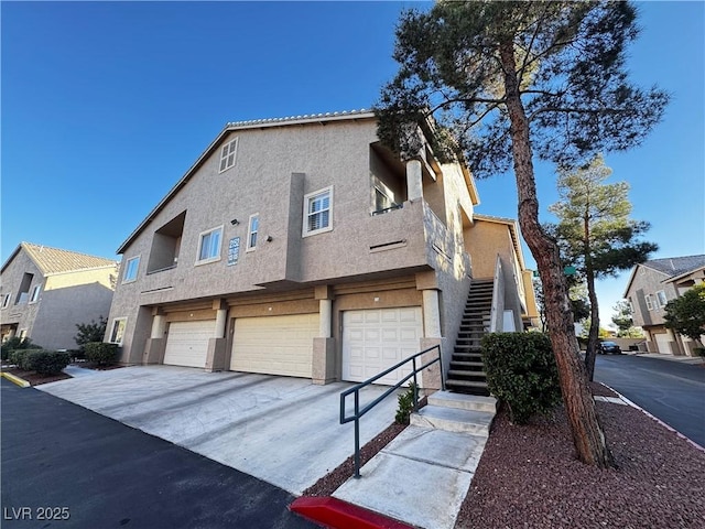 view of front of house with a garage, stucco siding, driveway, and stairs