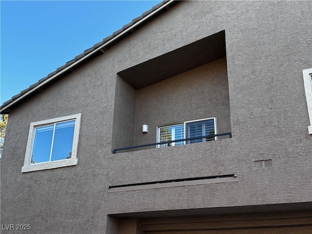 view of side of home with a tile roof and stucco siding