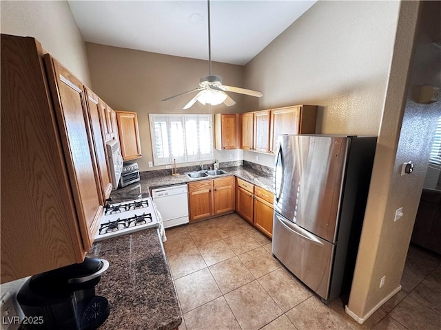 kitchen featuring white appliances, light tile patterned floors, brown cabinets, and a sink