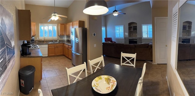 kitchen with dark countertops, freestanding refrigerator, open floor plan, a sink, and dishwasher