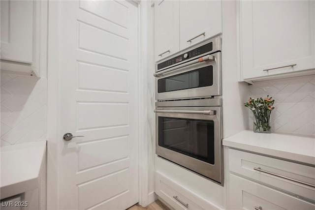 kitchen featuring tasteful backsplash, white cabinets, and double oven