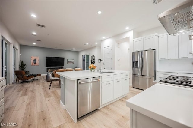 kitchen with sink, stainless steel appliances, an island with sink, white cabinets, and exhaust hood