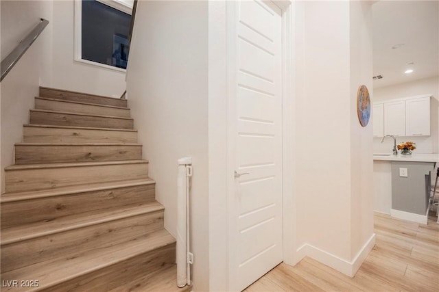 staircase featuring wood-type flooring and sink