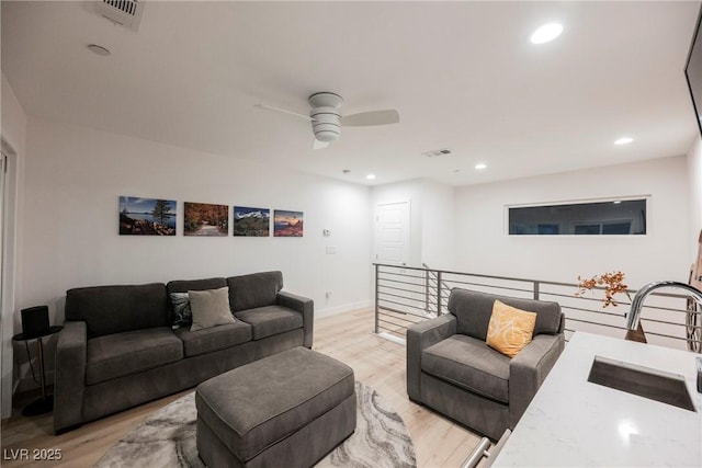 living room with ceiling fan, sink, and light hardwood / wood-style floors