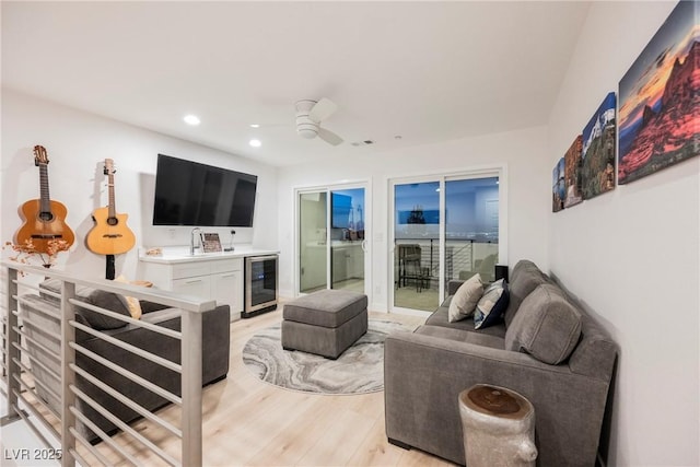 living room with ceiling fan, beverage cooler, and light hardwood / wood-style floors