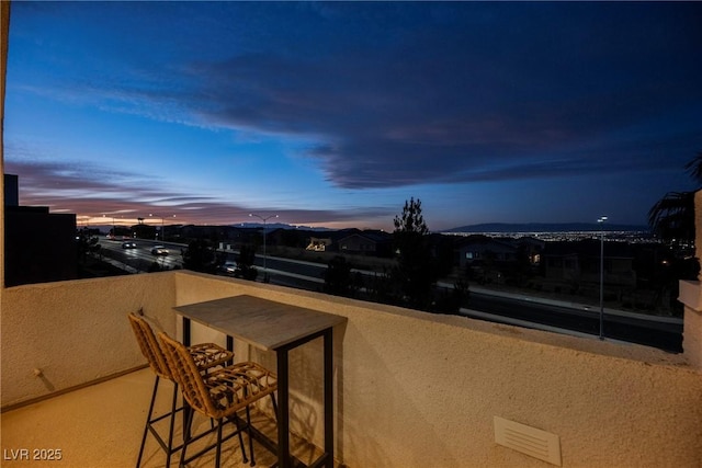 patio terrace at dusk featuring a balcony