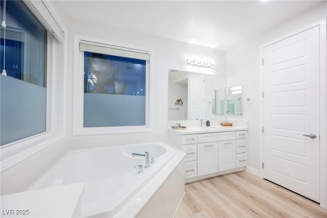 bathroom featuring vanity, a tub to relax in, and hardwood / wood-style floors