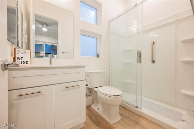 bathroom with wood-type flooring, toilet, an enclosed shower, and vanity