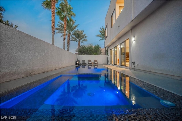 pool at dusk with a patio area