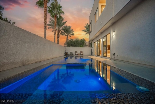 pool at dusk with a patio