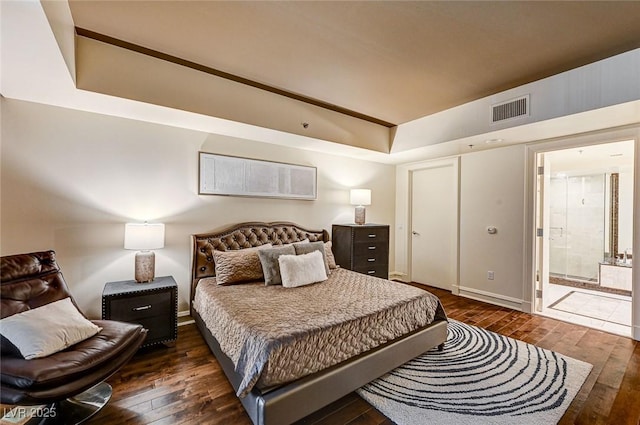 bedroom featuring connected bathroom and dark hardwood / wood-style floors