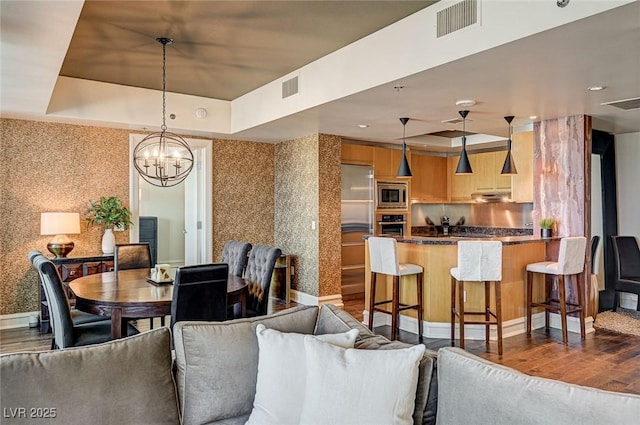 dining area with wood-type flooring, a tray ceiling, and a chandelier