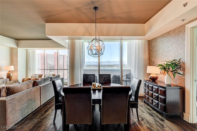 dining area with a healthy amount of sunlight, dark wood-type flooring, and a chandelier