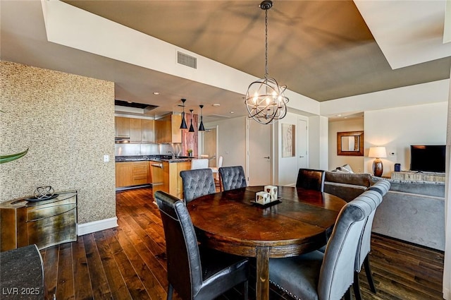 dining area featuring an inviting chandelier, dark wood-type flooring, and a raised ceiling