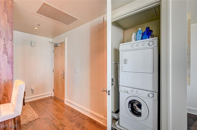 clothes washing area with stacked washer and dryer and wood-type flooring