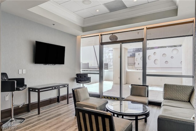 living room with crown molding, a tray ceiling, and light hardwood / wood-style floors