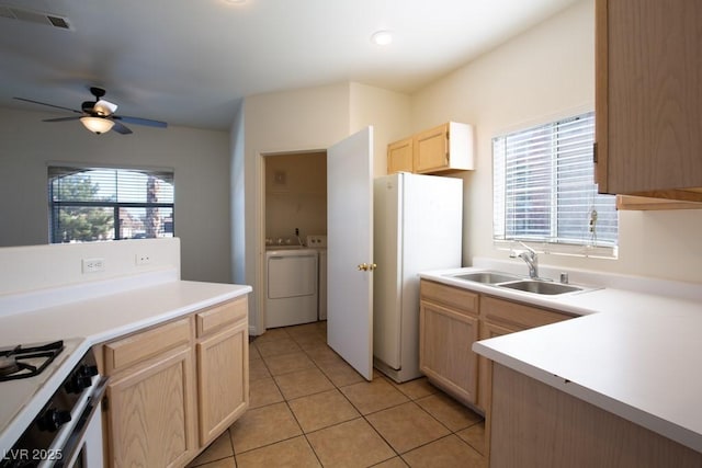 kitchen with sink, light tile patterned floors, washing machine and clothes dryer, and light brown cabinetry