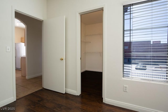 interior space with dark wood-type flooring, a walk in closet, a closet, and white fridge